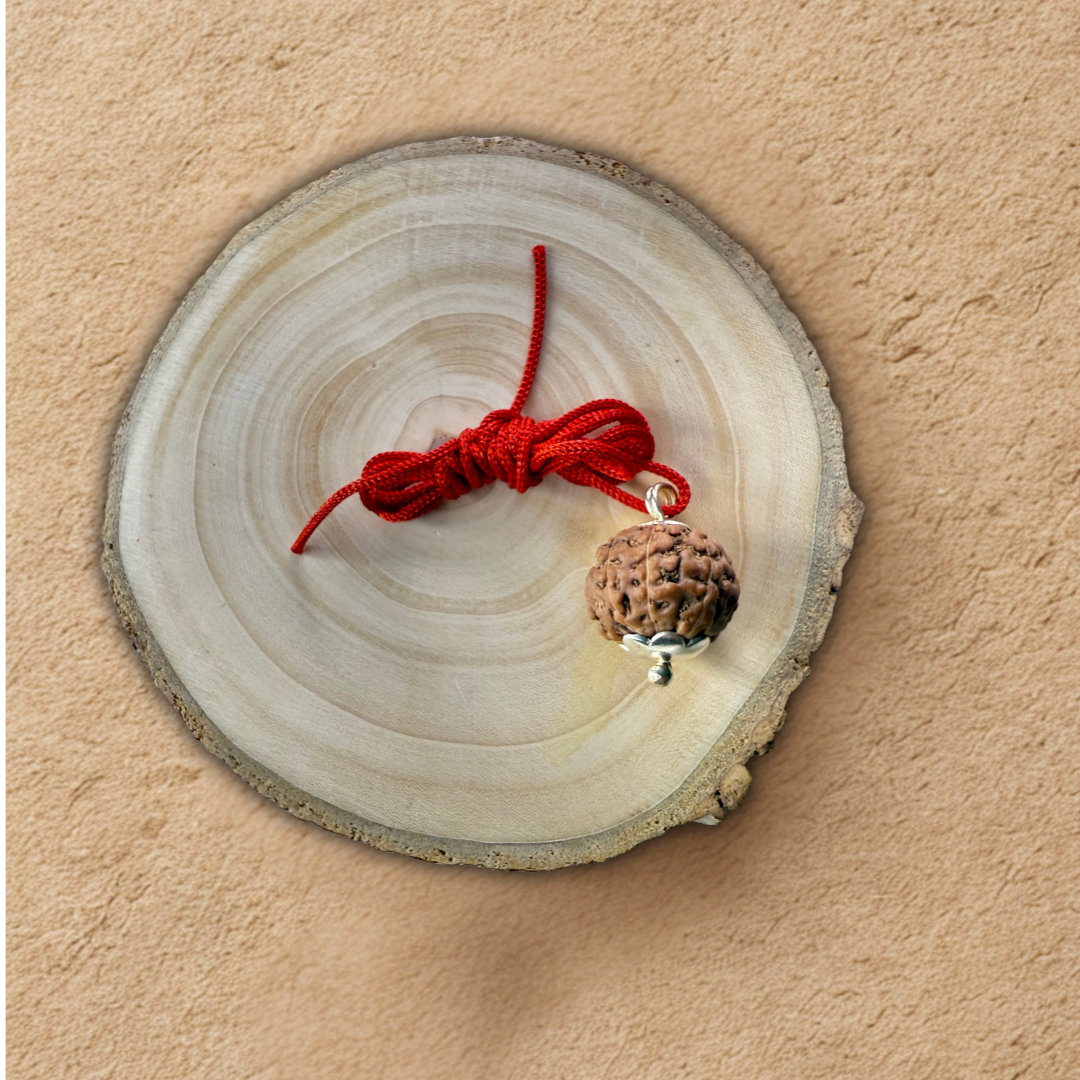 Wooden circular cutout with a red string and small pine cone on a beige background