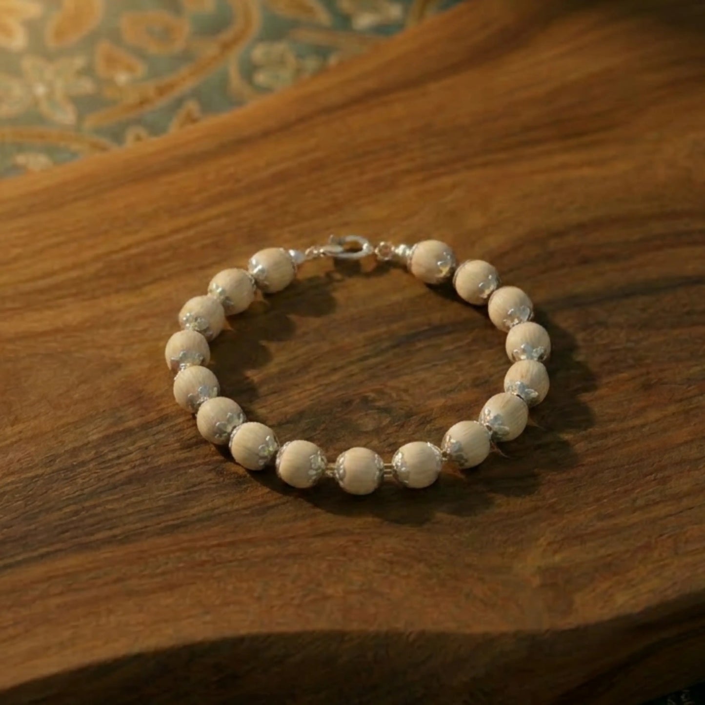 silver plated tulsi bracelet on sandalwood table 10mm 17 beads