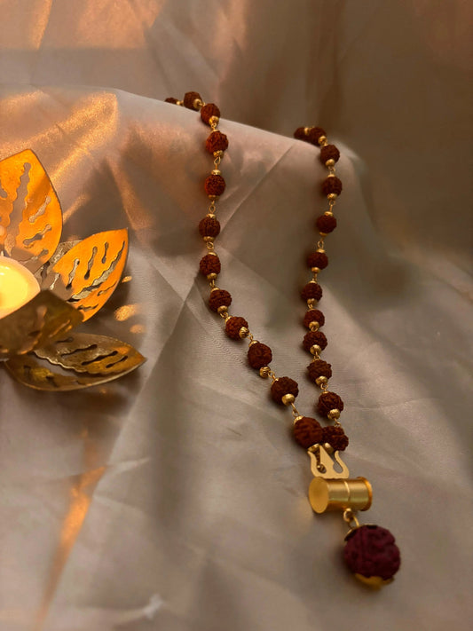 Necklace with maroon beads and gold accents on a textured fabric background Rudraksha Mala